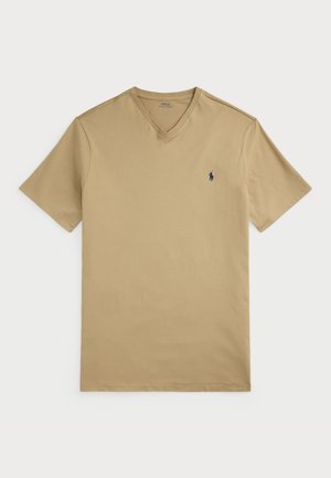 T-shirt beige en col en V en coton avec des manches courtes. Présente un petit logo bleu marine sur la poitrine gauche et une texture douce.