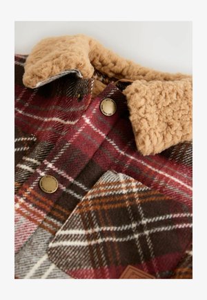 Karovaná košeľa s červenými, hnedými a krémovými odtieňmi, so svetlohnedým chmýřovým golierom, kovovými gombíkmi a prednou vreckom s hnedým nášivkom.