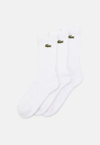 Drei Paar weiße Baumwollsocken mit gerippter Textur, jede Socke mit einem kleinen grünen gestickten Krokodil-Logo.