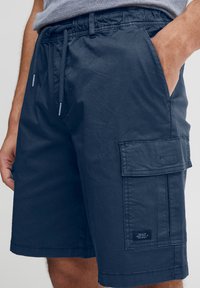 Námořnické cargo šortky z lehké látky, vybavené bočními kapsami, elastickým pasem a kapsou cargo s označením značky.