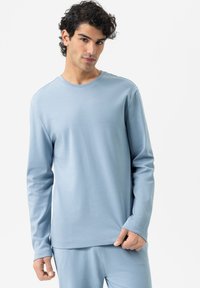 Hellblaues Langarmshirt aus weichem Material mit Rundhalsausschnitt und anliegenden Ärmeln, das eine glatte Textur und ein minimalistisches Design aufweist.