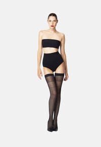 Sort bandeau-top parret med højtsiddende sorte shorts. Modellen har sorte fiskenet-strømper, der går op til lårene. Glat tekstur, tætsiddende design.