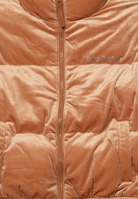 Gilet imbottito in morbido velluto arancione bruciato con una zip frontale, due tasche e logo "Juicy Couture" ricamato in argento.