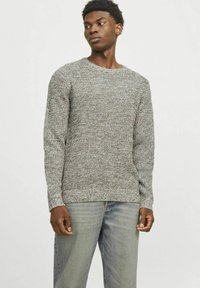 Suéter gris de punto con cuello redondo, patrón texturizado y mangas largas, combinado con jeans de un azul claro.