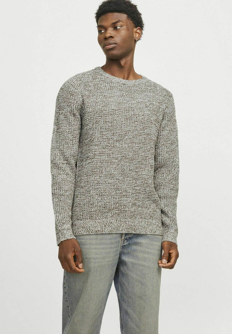 Suéter gris de punto con cuello redondo, patrón texturizado y mangas largas, combinado con jeans de un azul claro.