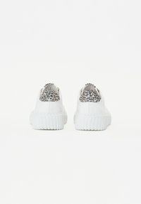Weiße Sneakers mit einer strukturierten Sohle, die einen Leopardenmuster-Akzent an der Ferse aufweisen. Glattes Material für den oberen Teil. Runde Form.