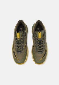 Grüne Sportschuhe mit Obermaterial aus Mesh, schwarzen und gelben Akzenten, runder Zehenpartie, Schnürdesign und strukturiertem Zwischensohle.