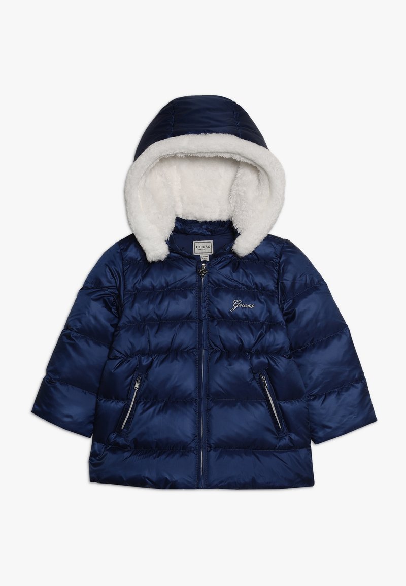 Granatowa kurtka puchowa z białym, futrzanym kapturem, z zamkiem z przodu, zamykanymi kieszeniami oraz logo "Guess" na klatce piersiowej, zaprojektowana na chłodne dni.