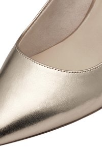 Metalne zlato špicasti pump s teksturiranom kožnom gornjom površinom i glatkim unutrašnjim oblogom. Ima čiste šavove duž ruba.