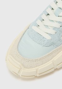 Baskets bleu clair avec des textures mélangées, y compris du suède doux et un tissu lisse. Elles sont dotées de lacets blancs et d'une semelle épaisse de couleur crème.