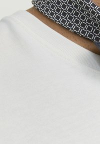 T-shirt in cotone bianco con scollatura a coste e colletto blu a fantasia con forme geometriche e dettagli.