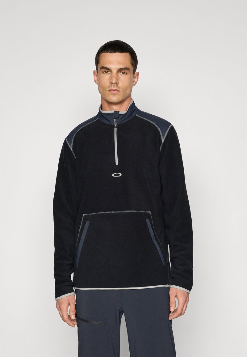 Black fleece pullover with a high collar, half-zip, contrasting blue accents, and gray stitching; features a front pocket.