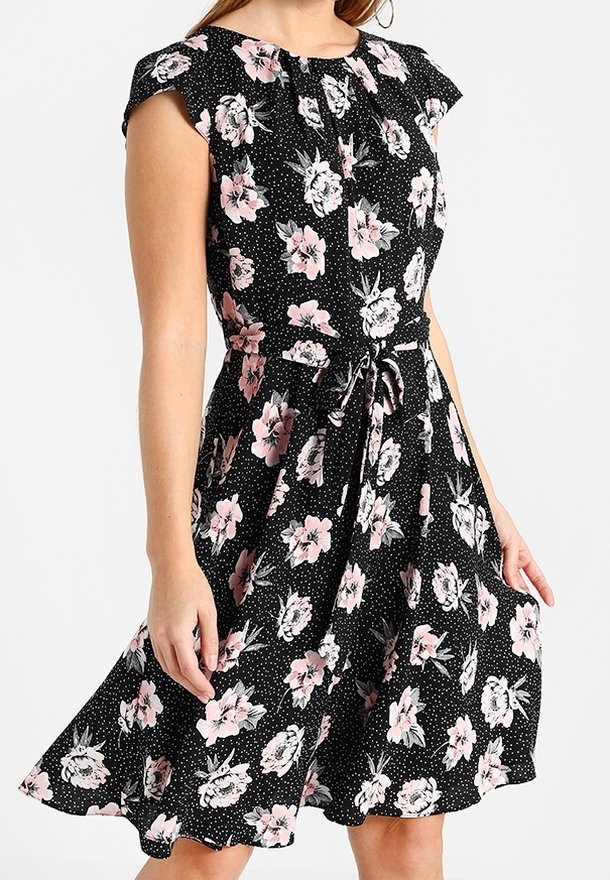 Czarna sukienka w kwiaty z krótkimi rękawami, ozdobiona różowymi kwiatami i kropkami, z talią podkreśloną szarfą oraz rozkloszowanym dołem.