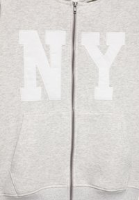 Sweat à capuche gris clair zippé avec de grandes lettres blanches "N" et "Y" sur le devant et deux poches avant.