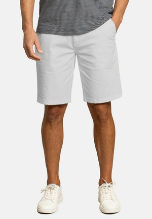 Shorts de algodón blancos con corte recto, bolsillos laterales y una textura suave, combinados con zapatillas blancas y una camisa estampada.