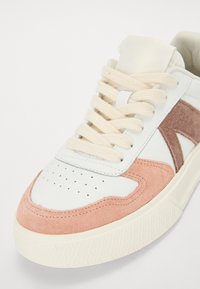 Sneaker met een witte leren bovenkant en roze suède accenten, beige veters, perforated teen en een gestructureerde crème rubberen zool.