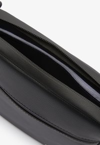 Borsa nera con un rivestimento in tessuto testurizzato e dettagli in pelle liscia. Presenta una chiusura con zip e un interno foderato con una leggera lucentezza.