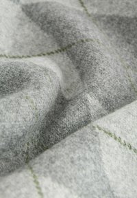 Tissu à carreaux gris avec une texture douce, rehaussé de surpiqûres vertes et de variations de tons gris clair et foncé, mettant en valeur la profondeur du tissu.