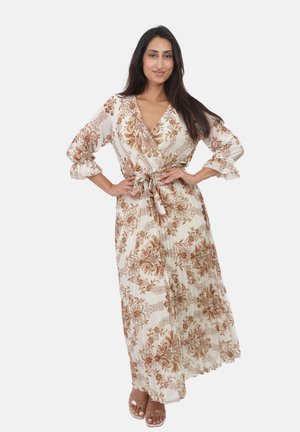 Lange, vloeiende maxi-jurk in crème met een bruin bloemenpatroon, V-hals, striktaille en gathered mouwen. Lichtgewicht, geplooide textuur.