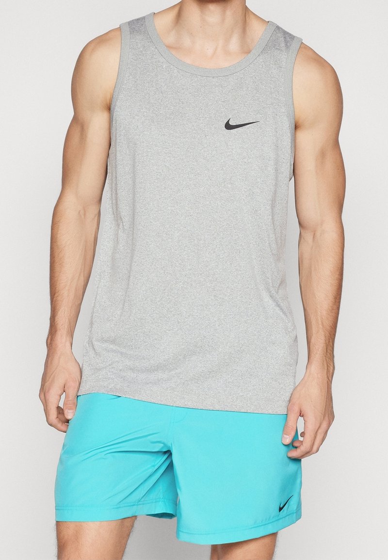 Camiseta de algodón gris sin mangas con cuello redondo y logotipo negro de Nike, combinada con pantalones cortos deportivos azules que presentan un diseño sin costuras.