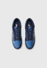 Sapatilhas Nike em azul marinho e azul, com parte superior em couro e têxtil, bico arredondado, detalhes perfurados e atacadores planos. Sola em borracha branca.