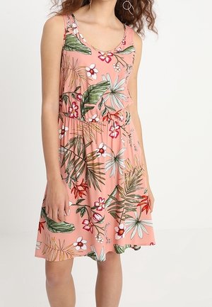 Sleeveless pink dress with tropical floral print, fitted waist, and round neckline worn by a standing person against a plain background.