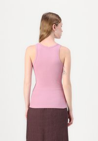 Rosa geripptes Tanktop mit taillierter Passform. Verfügt über einen runden Ausschnitt und ärmellosen Schnitt. Glatte Textur, minimale Details auf der Rückseite.