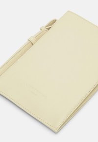 Żółty skórzany portfel o gładkiej fakturze, z przeszytym brzegiem i bezpiecznym zapięciem na sznurek. Delikatne tłoczone logo z przodu.