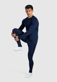 Marinblå atletisk baslager-set, långärmad topp och tajta leggings, slät textur, åtsittande passform, med kontrasterande vita strumpor.