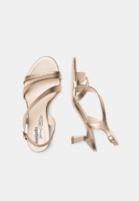 Gold metallic high-heeled sandals with multiple crisscross straps and a buckle closure. Features a modest heel and smooth, glossy surface.
