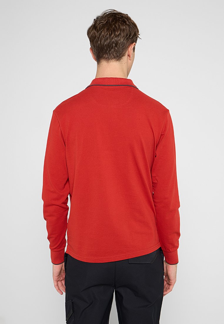 Camisa polo de manga larga en rojo brillante, hecha de tela suave. Cuenta con un cuello y un dobladillo recto, con un diseño minimalista y sin adornos.