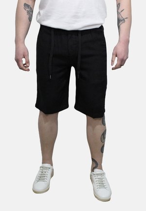 Pantaloni corti neri realizzati in tessuto leggero, dotati di una vita elastica con cordini e tasche laterali. Abbinati a Sneakers bianche.