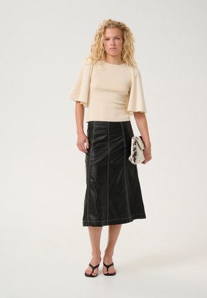 Beige kortærmet top med flagrende ærmer, parret med en sort læder midi nederdel med hvid syning. Accessories inkluderer en pels clutch.