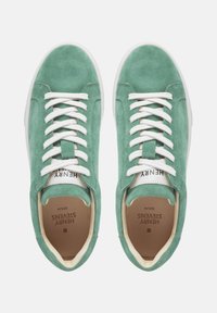 Sneakers in suede verde con lacci bianchi, interno beige e un'etichetta con il logo sulla linguetta. Design con punta arrotondata e suola piatta in gomma.