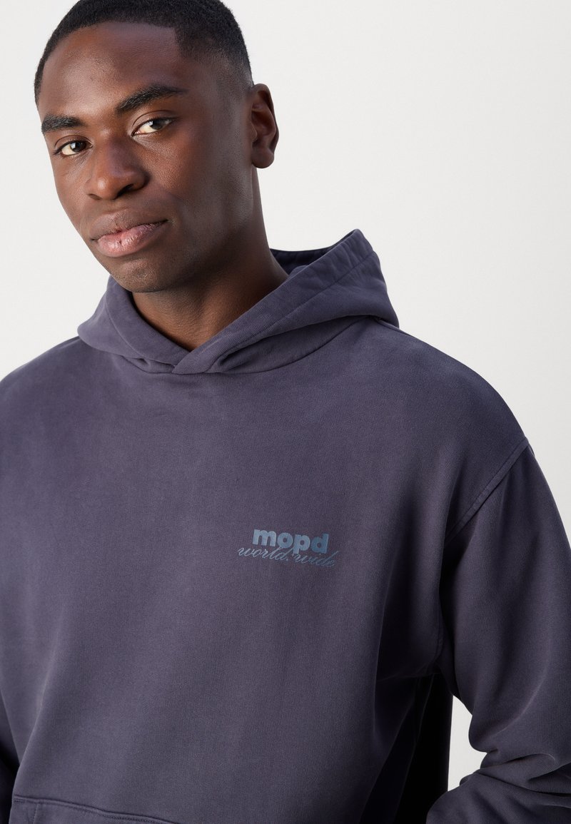 Violetter Hoodie mit Kängurutasche, verstellbarem Kordelzug an der Kapuze und gesticktem Logo auf der Brust. Weicher Stoff mit angenehmer Textur.