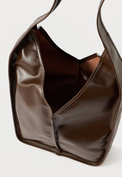 Barna bőrtáska puha, fényes felülettel, nyitott felső résszel és dekoratív varrással az éleken. Belseje kontrasztos sötét színárnyalatú.