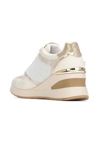 Zapatilla cuña en blanco con tela texturizada, detalles dorados y una suela acolchada. Presenta paneles de malla y un diseño elegante.