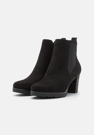 Bottines en suede noir avec des panneaux latéraux élastiques, bout rond et un talon épais. Surface texturée avec des accents lisses sur le talon.