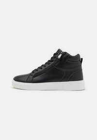Zapatillas altas negras con un acabado de cuero suave, suela de goma blanca, cordones en la parte frontal y detalle de cremallera lateral.