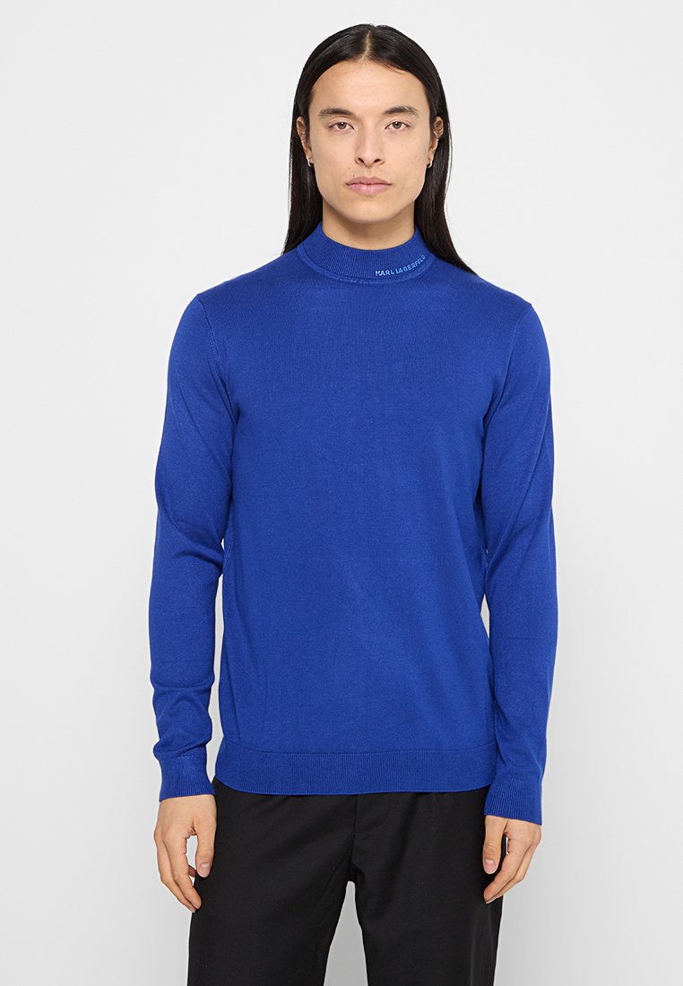 Blauer Strickrollkragenspullover mit langen Ärmeln. Verfügt über gerippte Bündchen und Saum. Subtile Markenkennung nahe dem Kragen. Glatte Textur.