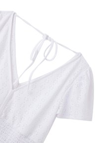 Abito bianco con maniche a sbuffo corte, caratterizzato da un tessuto testurizzato con motivi a occhietti e una scollatura a V sul retro, fissata da chiusure a lacci.