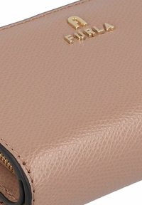 Cartera de cuero rosa claro con textura granulada, equipada con herrajes dorados y el logo "Furla" en relieve en el frente.