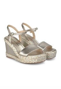 Sandales compensées en or métallisé avec une semelle en jute tressé. Présentent un design à bout ouvert et une sangle de cheville ajustable pour un maintien sécurisé.