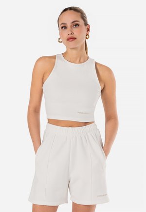 Top crop bianco a coste con scollo rotondo, abbinato a pantaloni corti bianchi coordinati con vita elastica e tasche laterali.