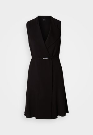 Zwarte mouwloze jurk met een V-hals en een getailleerde taille, voorzien van een zilveren gespdetail en een uitlopende rok. Gemaakt van een gladde stof.