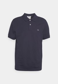 Navy blå polo skjorte laget av bomull. Har en klassisk krage, to-knapps placket og en liten brodert logo på venstre bryst.