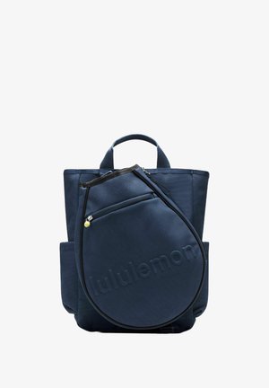 Tmavě modrý batoh s texturovanou látkou, horními uchy a přední kulatou kapsou na zip s vystouplým logem.