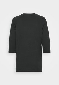 Svart skjorta med trekvartsärmar, i en mjuk textur och rundad halsringning. Har en avslappnad passform och raglanärmar.