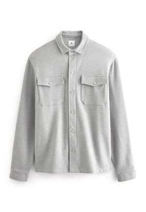 Graues Langarmshirt aus weichem Stoff, mit Knopfleiste, zwei Brusttaschen und klassischem Kragen.