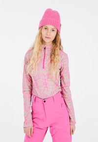 Haut léger à manches longues avec des motifs géométriques roses ; associé à un pantalon de ski ajusté rose vif avec des poches zippées et une taille haute.